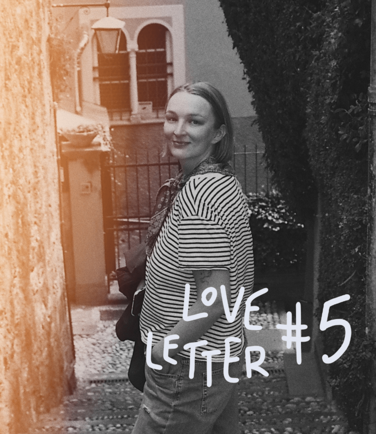 Woman in a picturesque alleyway looking directly into the camera over her shoulder